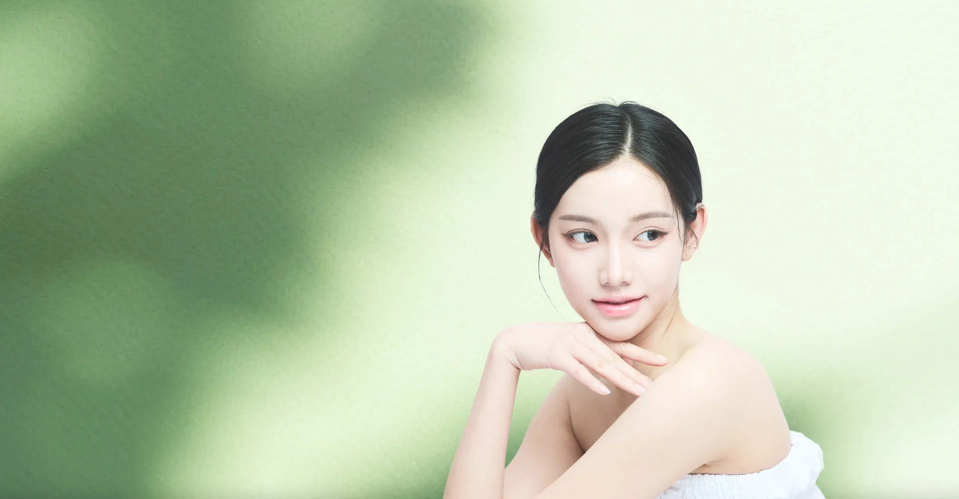 輪郭注射のイメージ：肩を出した女性が顎に手を当て、横を見ている。