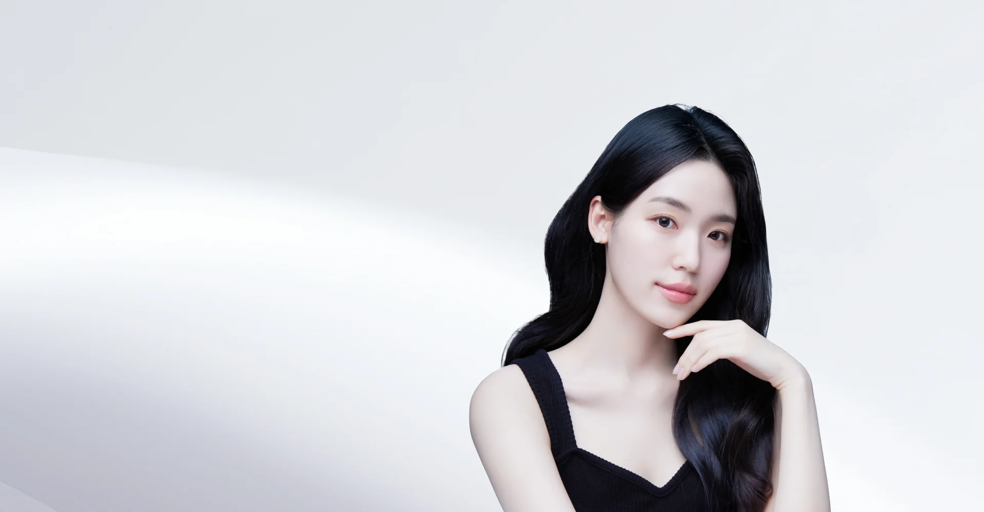 黒髪の女性が顎に手を当てて微笑んでいる、糸リフトのイメージ画像