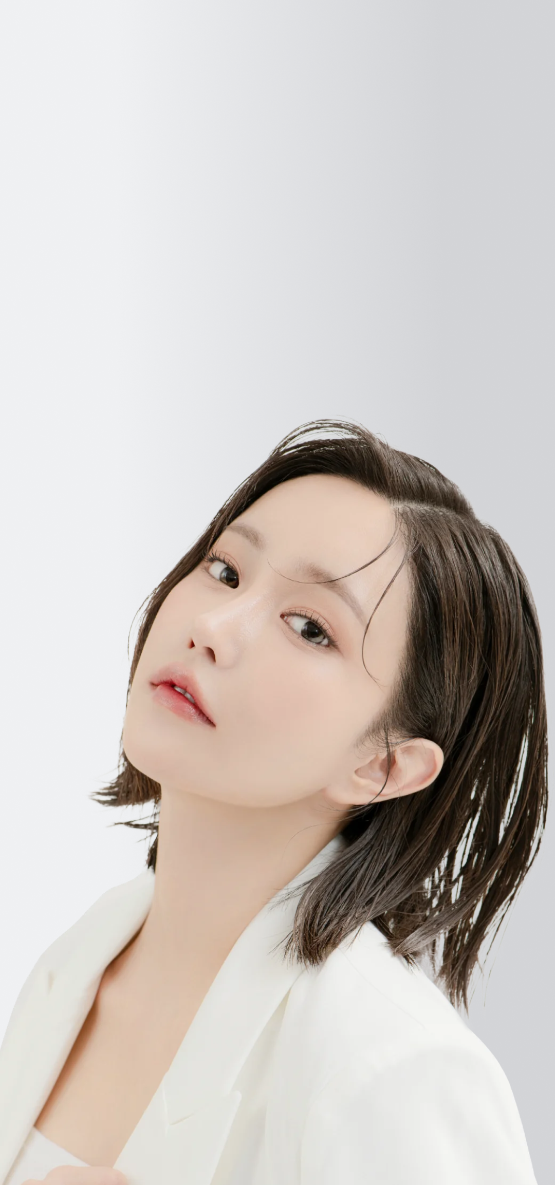 ショートヘアの女性が白いジャケットを着て、上を見上げている。